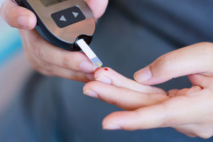 photo of finger being pricked for blood glucose for diabetes using a glucometer