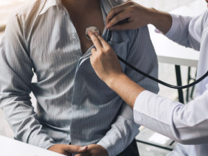 doctor checking mans heart beat